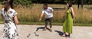 Die Spieler konzentrieren sich während einer Pétanque-Runde auf das Spielfeld und entscheiden, ob sie eine Kugel in der Nähe des Spieles platzieren oder die gegnerische Kugel treffen sollen.