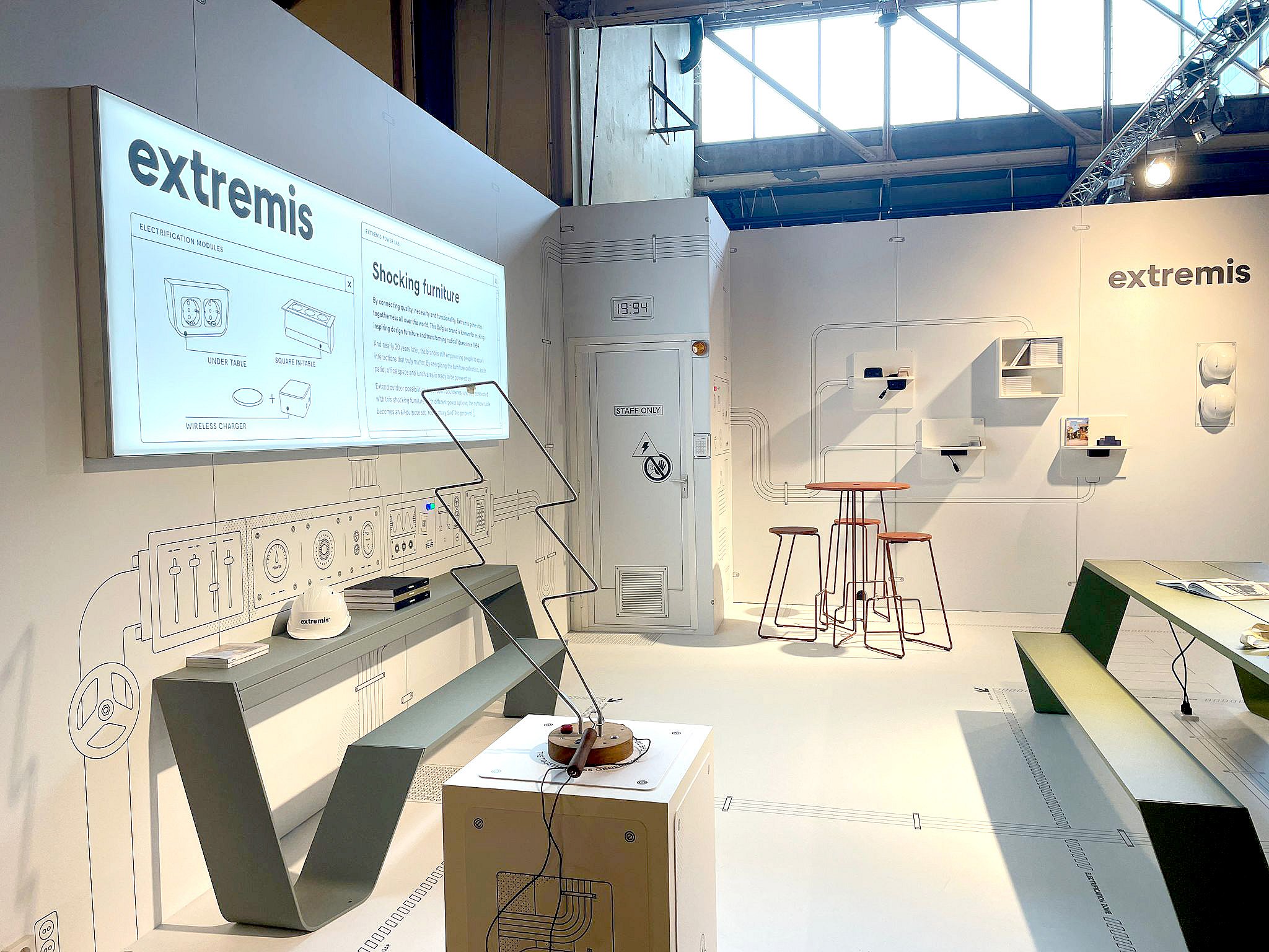 Gros plan sur le graphisme mural de l'exposition montrant le logo Extremis, un panneau avec le texte « Mobilier électrifiant » et des schémas de modules d'électrification.