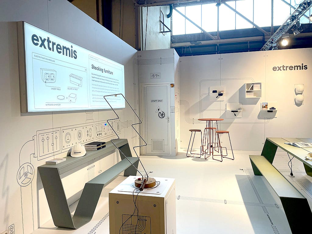 Gros plan sur le graphisme mural de l'exposition montrant le logo Extremis, un panneau avec le texte « Mobilier électrifiant » et des schémas de modules d'électrification.