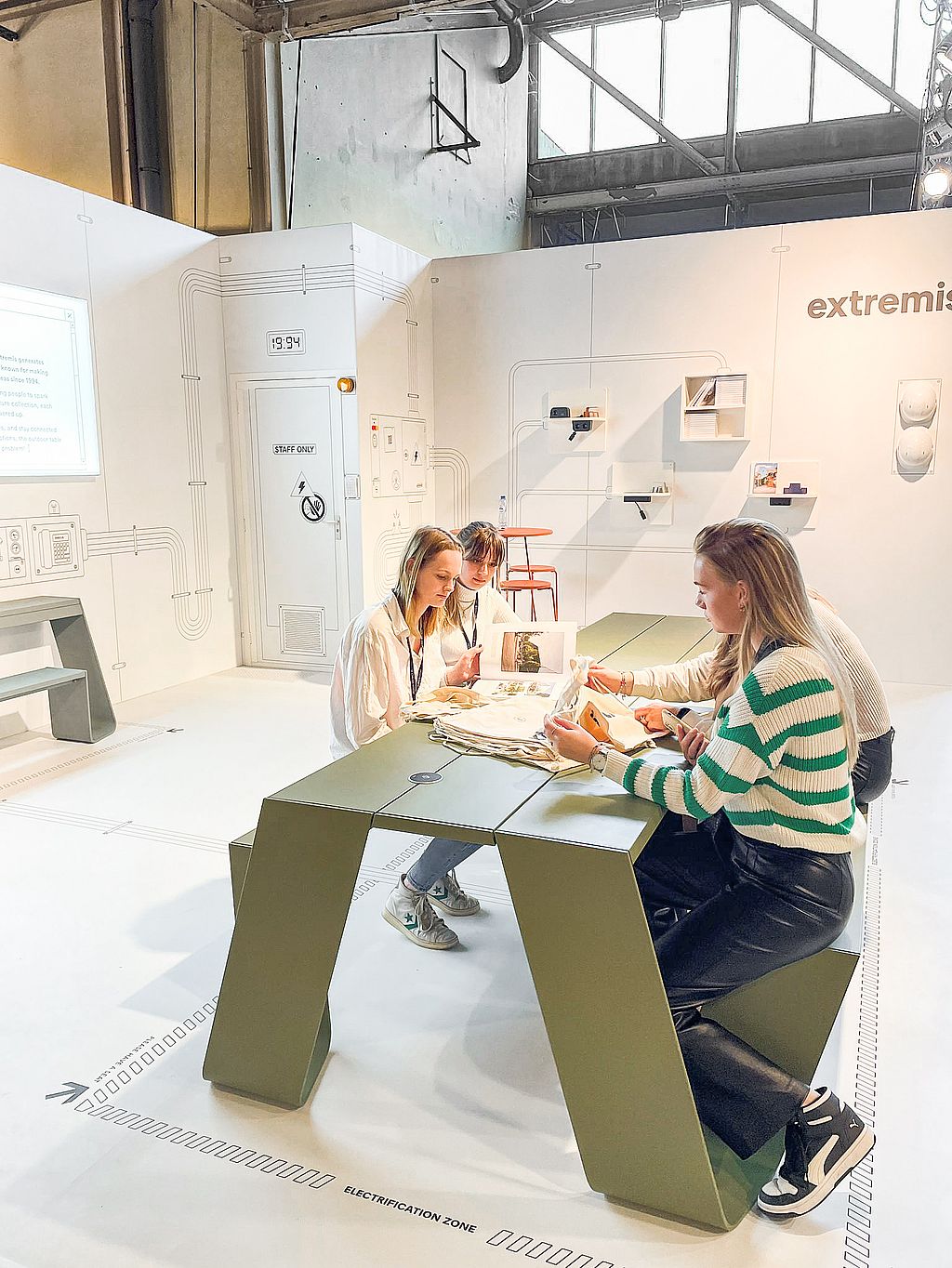 Une longue table verte et un banc avec un module d'alimentation noir intégré au plateau, présentés à l'intérieur de l'installation Power Lab.