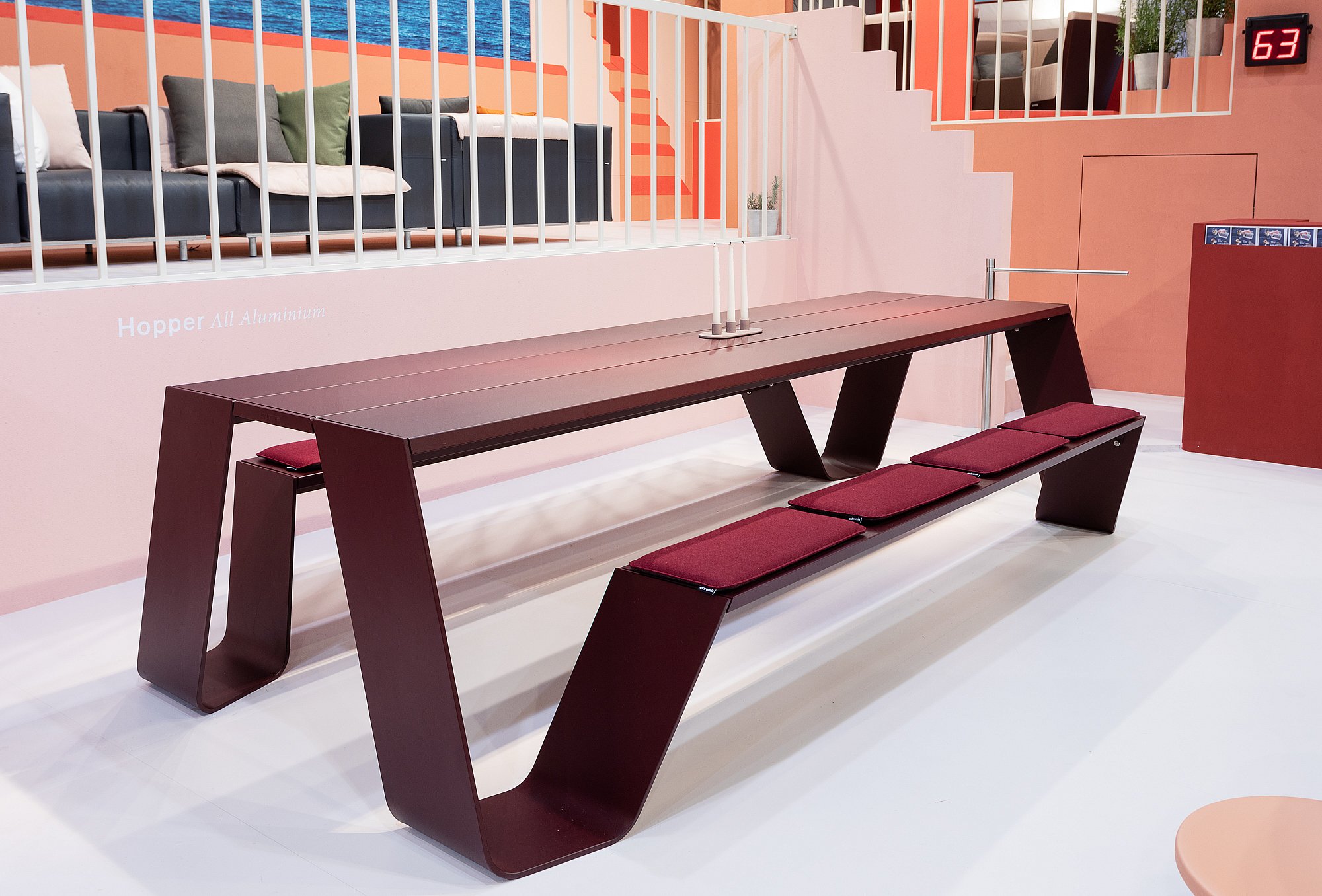 Dark burgundy Hopper All Aluminium picnic table with matching bench and seat cushions displayed in the pastel fair stand interior.