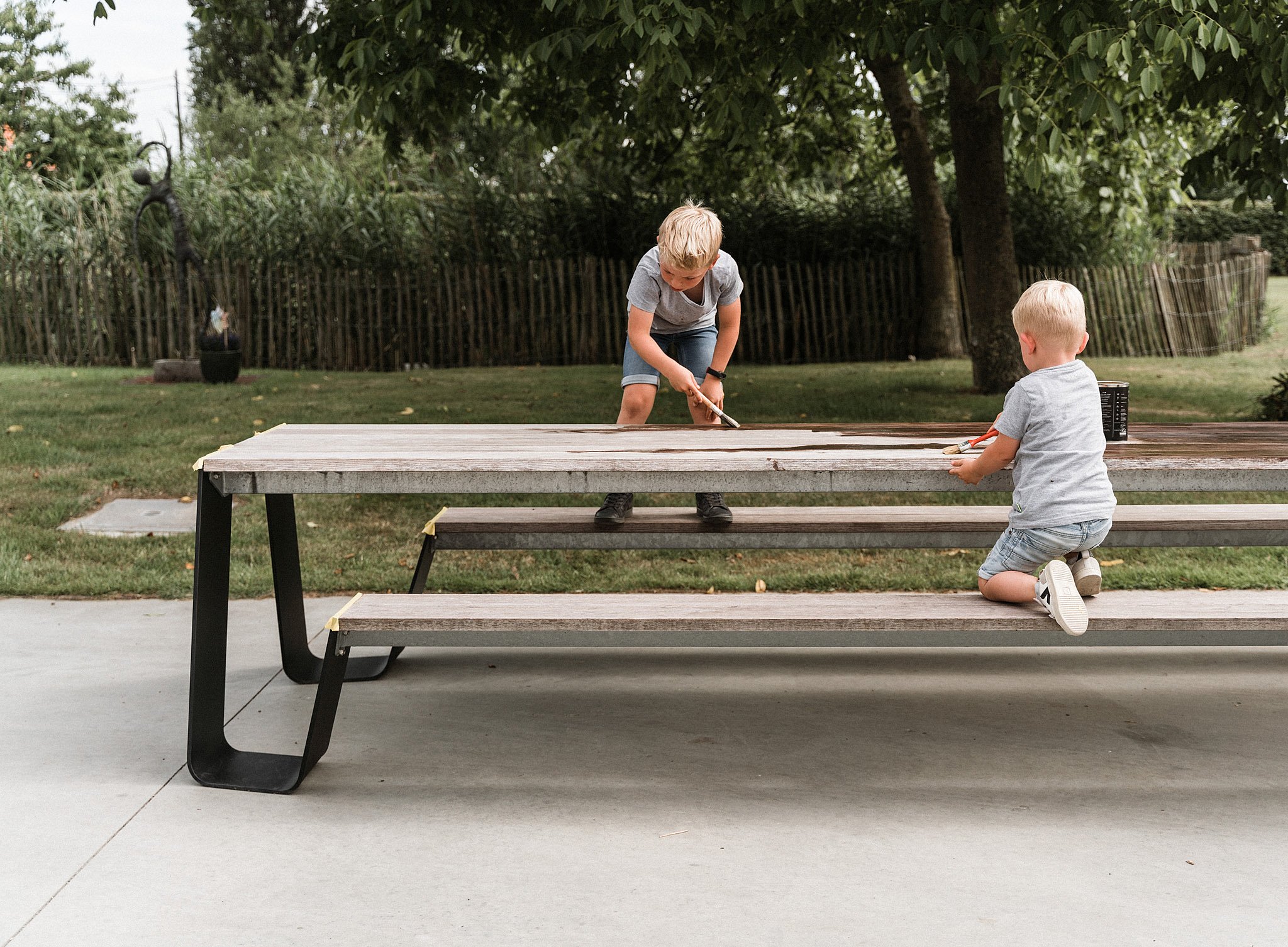 Family lente-reinigingsscène rond een houten buitentafel, die na de winter de jaarlijkse verfrissing van tuinmeubelen introduceert.