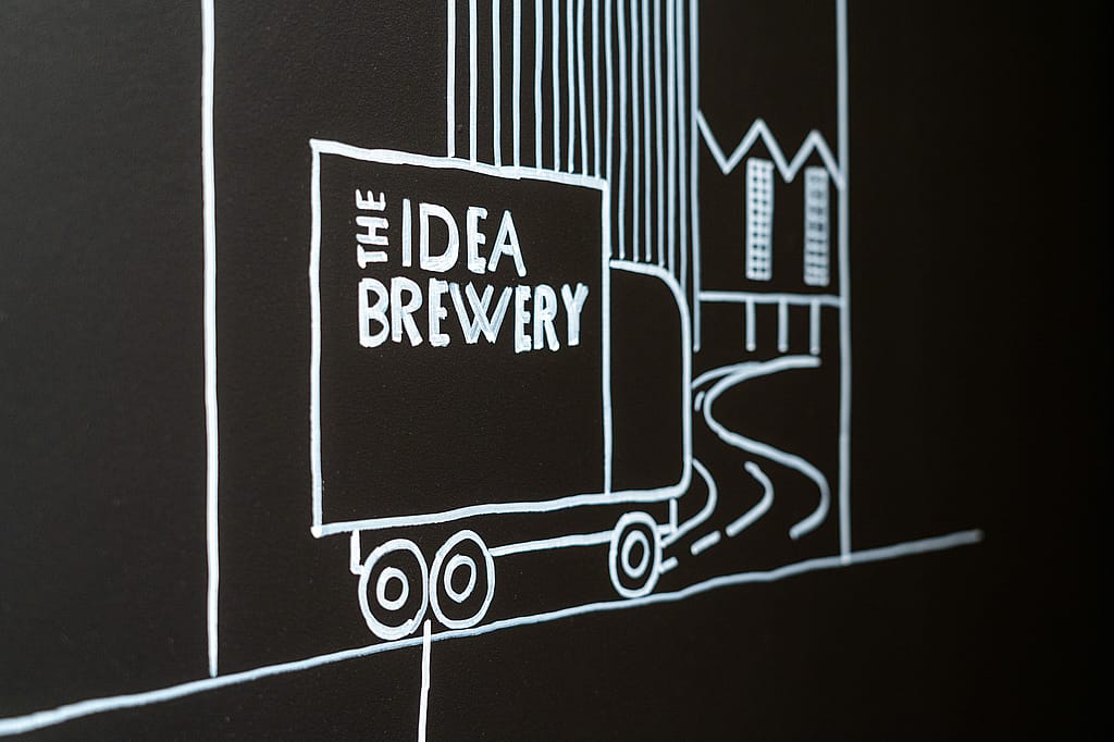 Nahaufnahme einer Wandzeichnung im Kreidestil eines Lieferwagens mit der Aufschrift ‘The Idea Brewery’, die Ideen vorschlägt, die aus dem Arbeitsbereichskonzept verschickt werden.