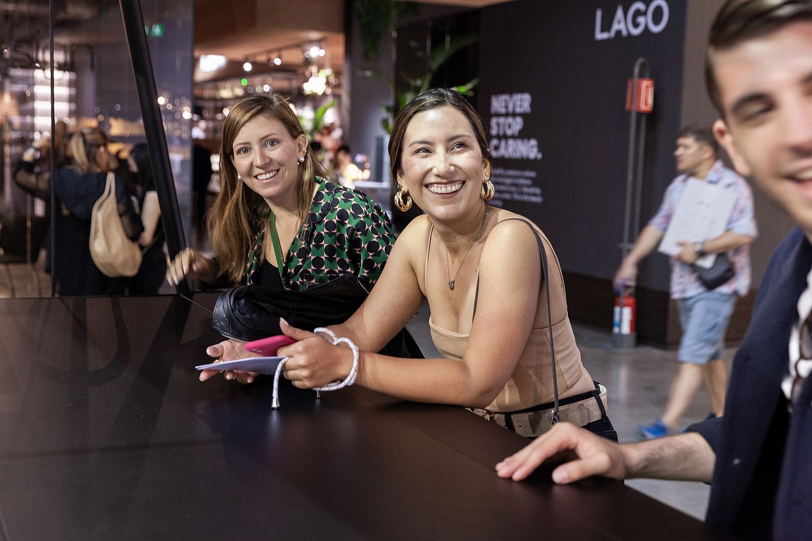 Image de style de vie AMAi supplémentaire du stand de Milan, montrant probablement des visiteurs rassemblés autour de la table flexible lors de la présentation de la fête dans le jardin.