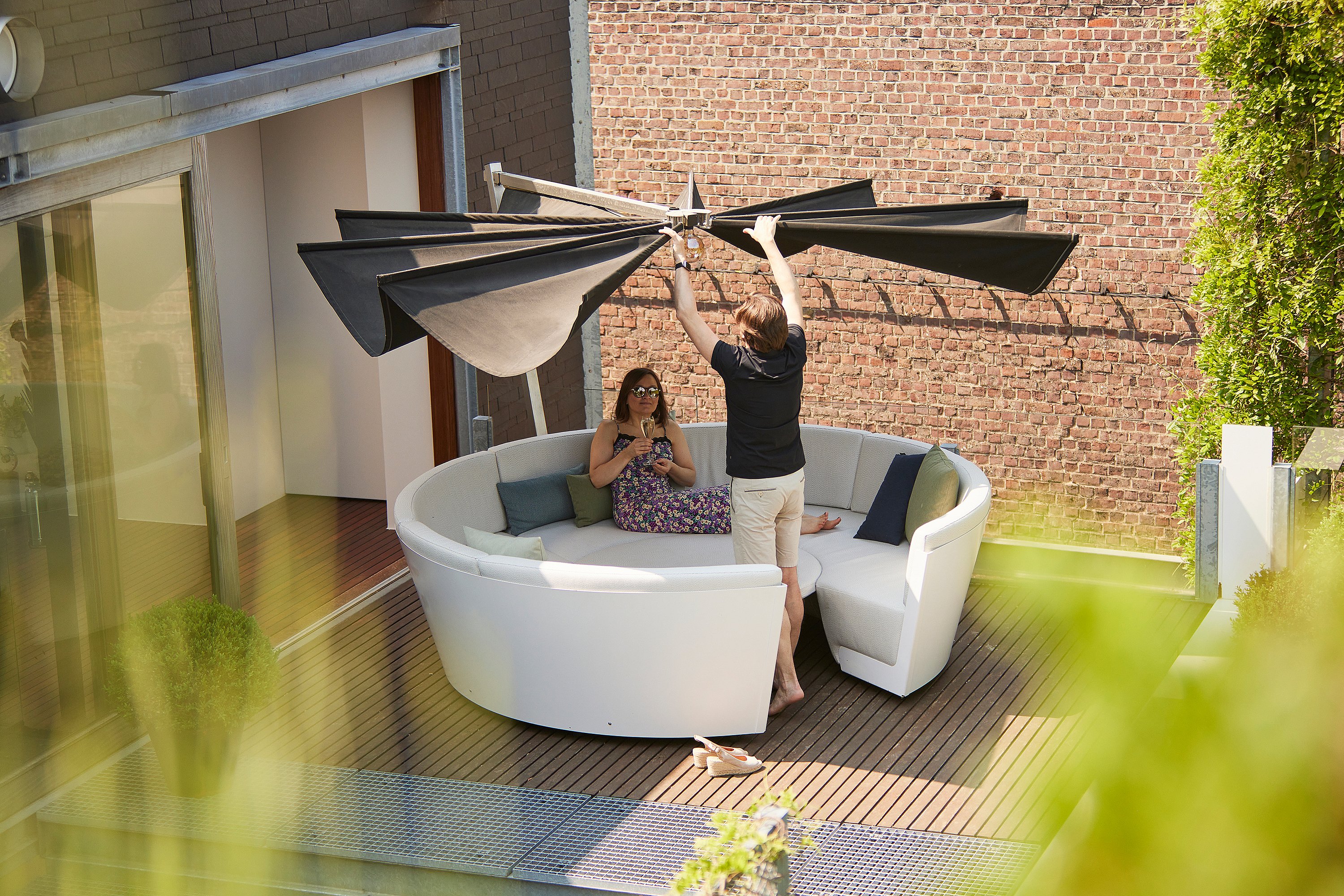 Kosmos shade with a broad horizontal canopy, designed to open like wings and create calm, understated shade above a seating area.