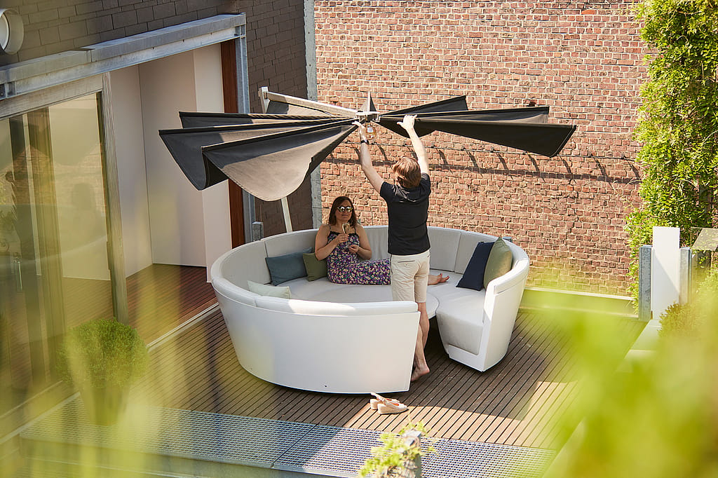Kosmos shade with a broad horizontal canopy, designed to open like wings and create calm, understated shade above a seating area.