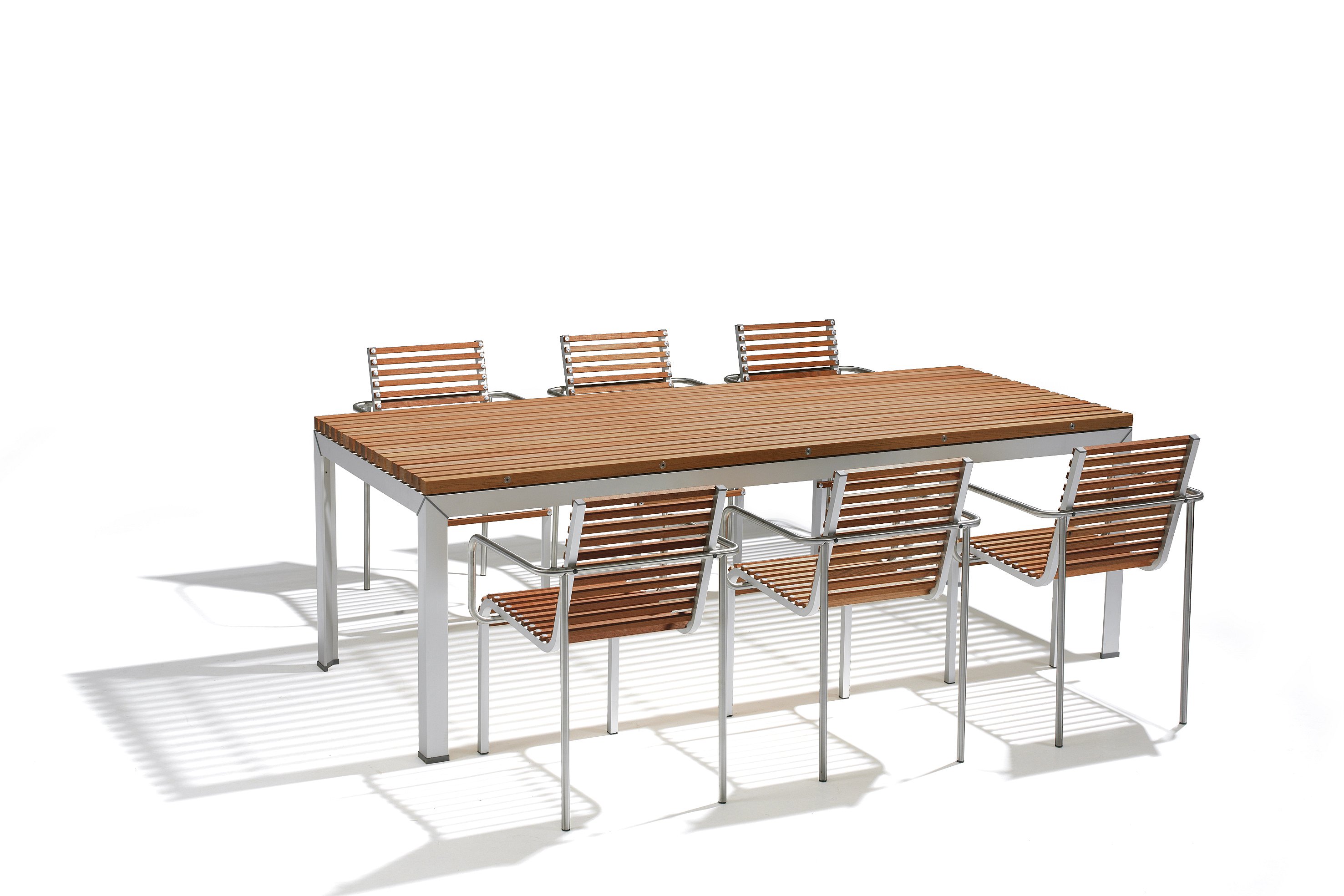 Close-up of a dark wooden slatted tabletop on a white metal frame, with matching slatted seating softly blurred in the foreground.