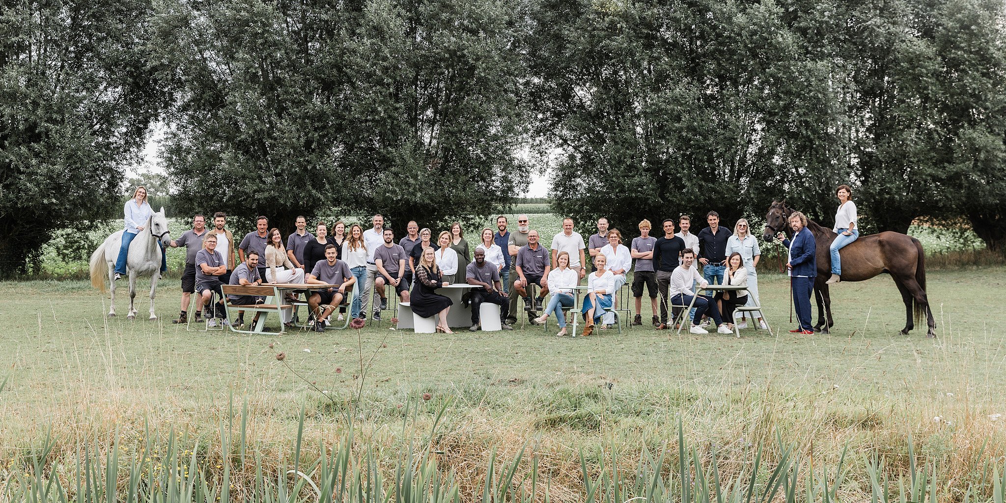 Extremis-team verzamelde zich buiten in een grasveld voor een groepsportret, met bomen en open landschap erachter.
