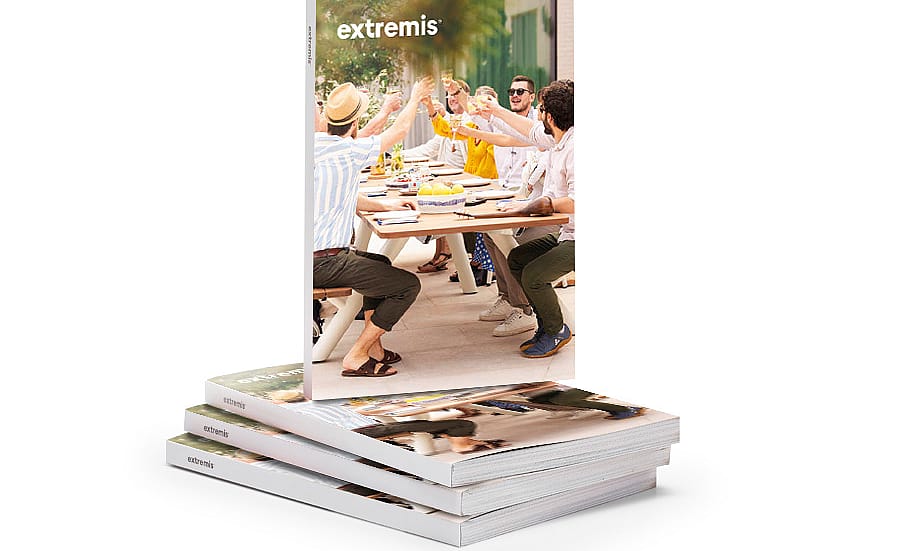 Stapel Extremis-catalogi met één rechtopstaande omslag met een groep mensen die rond een lange eettafel in de buitenlucht roosteren.