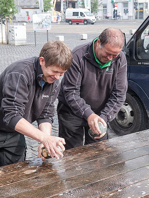 Verwitterter hölzerner Hopper-Picknicktisch, der draußen auf einem Marktplatz in Poperinge steht und vor dem Frühjahrsputz gezeigt wird.