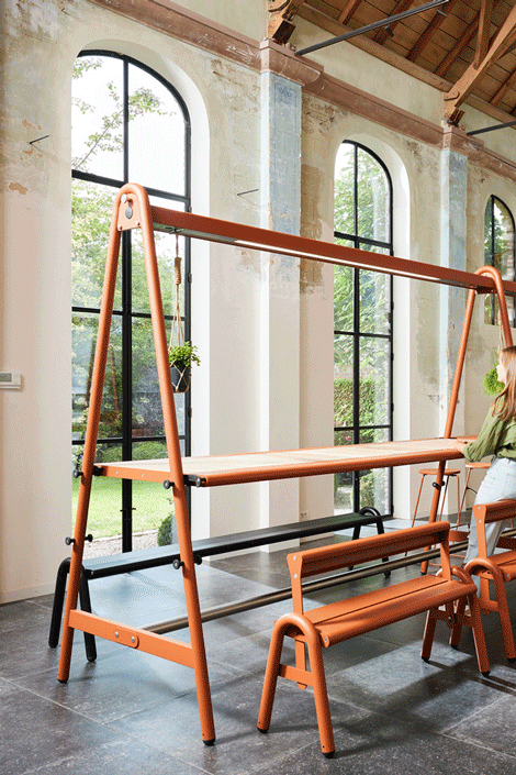Animated view showing the AMAi tabletop being adjusted between sitting and standing height within the A-frame structure.