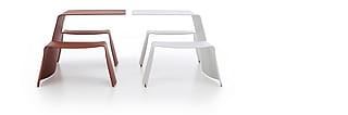 Studio shot of two picnik tables side by side, the left one being red, the right one white.