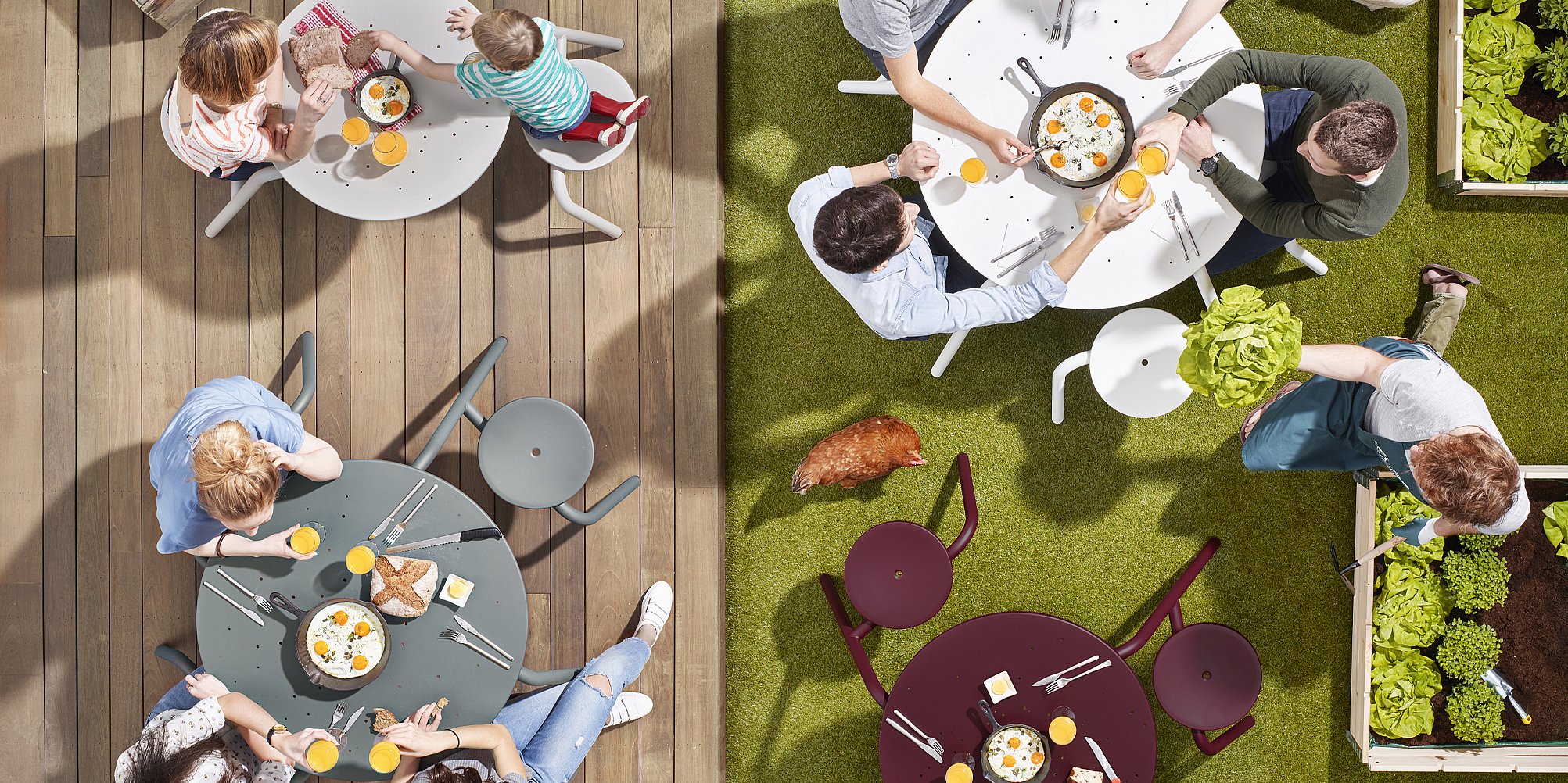 Draufsicht auf mehrere Virus-Picknicktische in verschiedenen Farben und Größen, die in einem geräumigen Indoor-Showroom aufgestellt sind. Besucher gehen zwischen den Tischen hindurch.