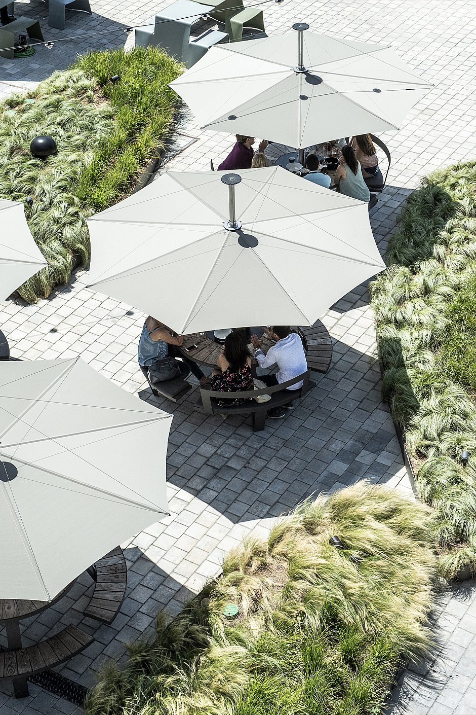 Inumbra shown in a real-life outdoor project setting, illustrating the parasol in terraces, gardens, hospitality spaces, and public environments.