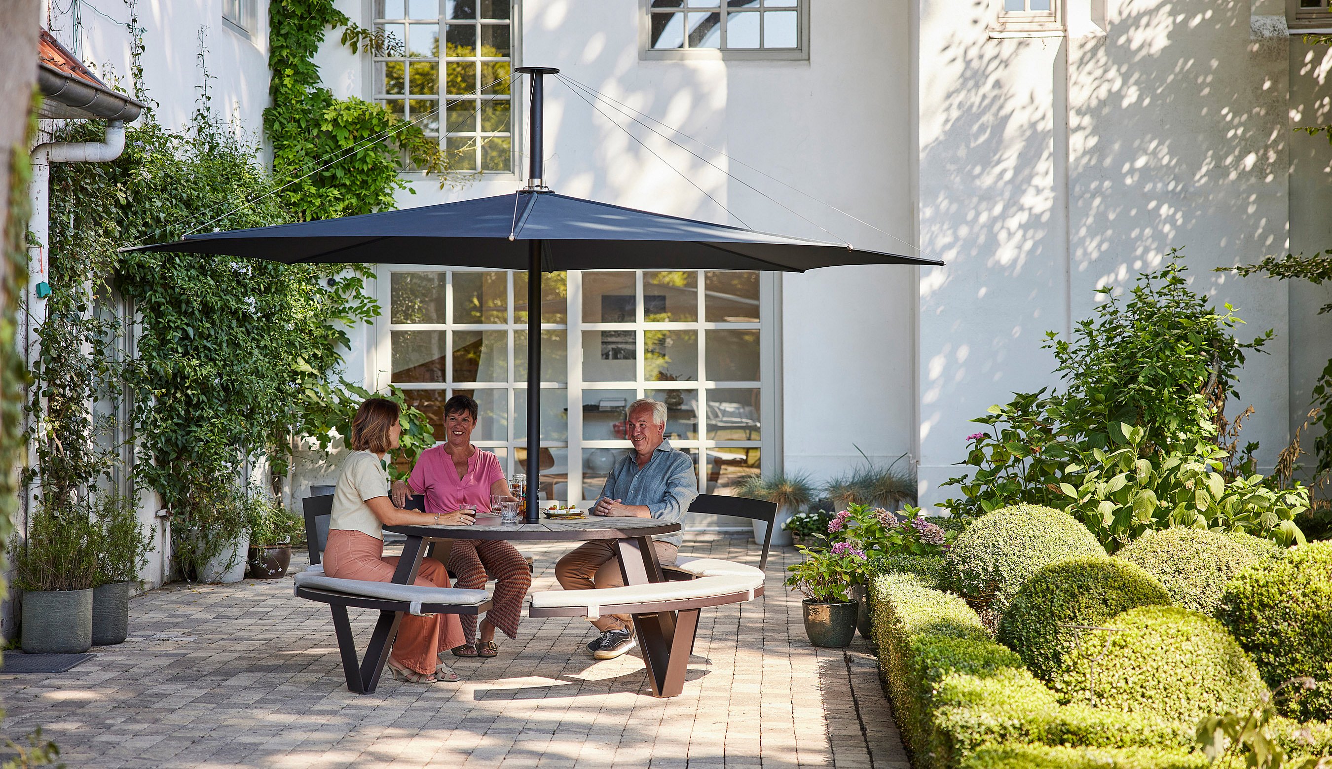 Inumbra shown in a real-life outdoor project setting, illustrating the parasol in terraces, gardens, hospitality spaces, and public environments.