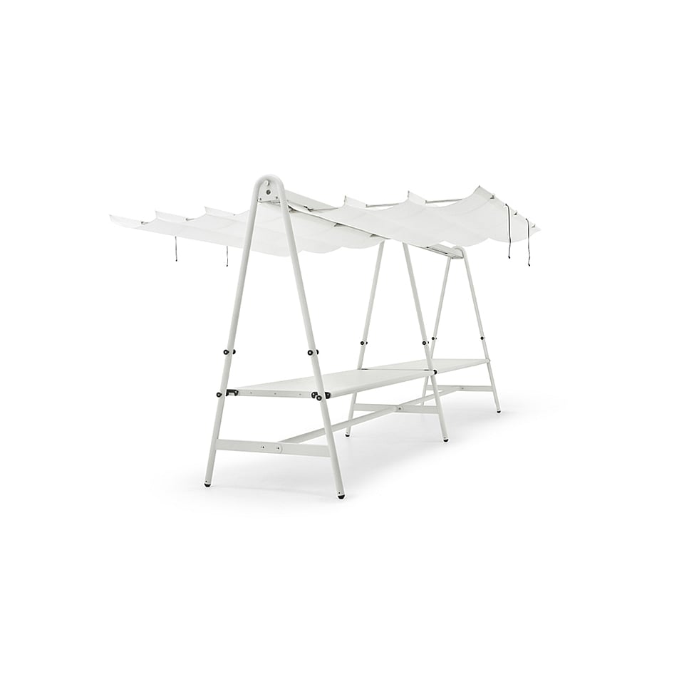 Studio view of a white AMAi table with A-shaped side frames, a long tabletop, and folded overhead shade panels.