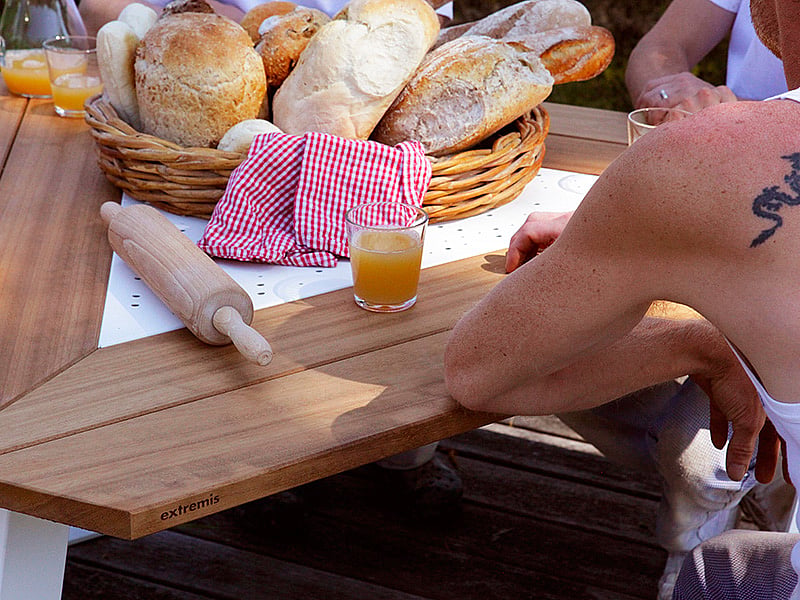 Korb mit frisch gebackenem Brot, Orangensaft und einem Nudelholz auf einem hölzernen Ankertisch