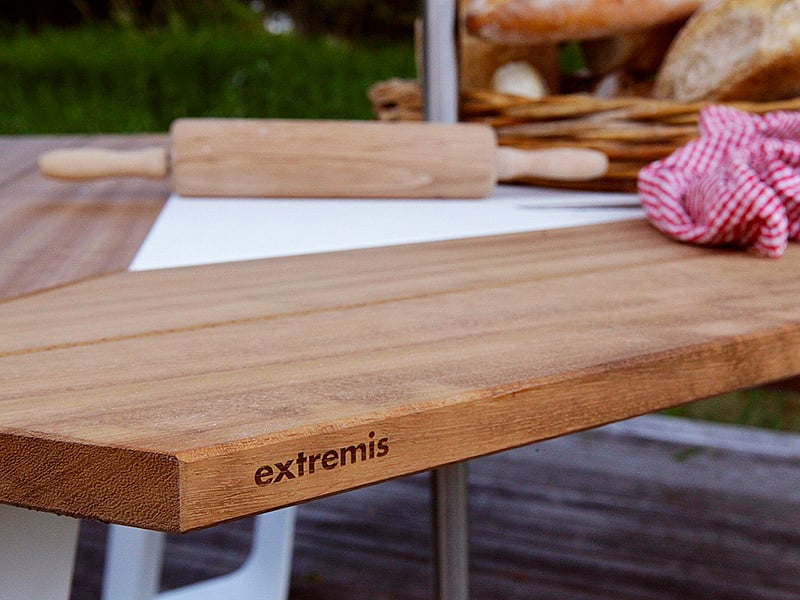 Nahaufnahme des Extremis-Logos auf der Holzkante eines Anker-Tisches mit Backartikeln darauf