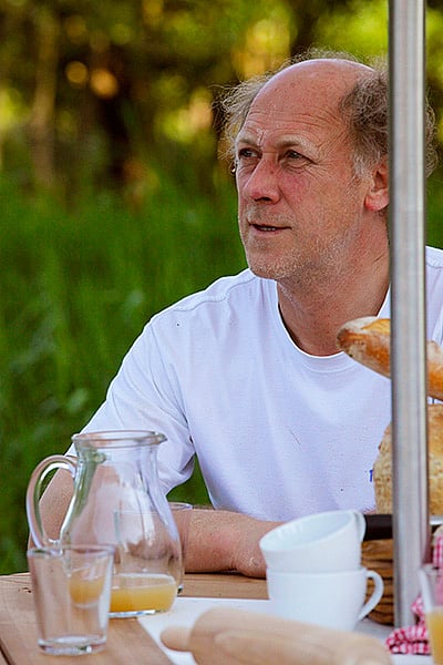 Bäcker sitzt während einer Pause im Freien mit Brot, Saft und Tassen an einem Ankertisch