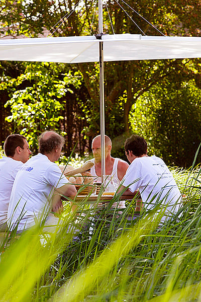 Vier Bäcker versammelten sich um einen Ankertisch unter einem Inumbrina-Schatten im Garten