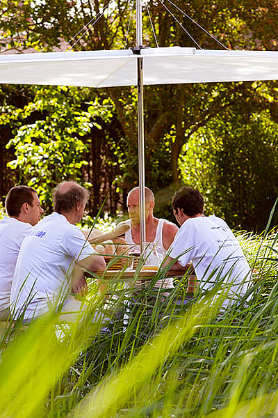 Vier Bäcker versammelten sich um einen Ankertisch unter einem Inumbrina-Schatten im Garten