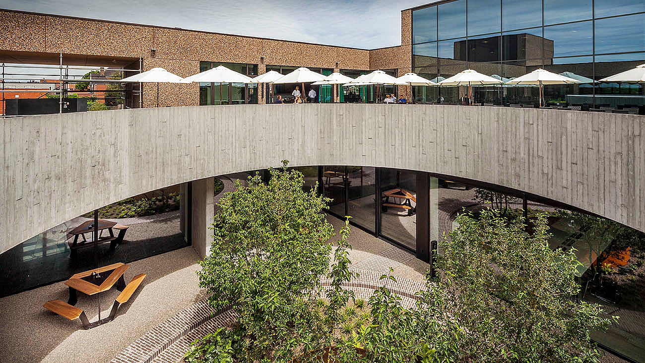 Binnenplaats met twee verdiepingen bij brouwerij Vanhonsebrouck met ankertafels, parasols en centrale beplanting