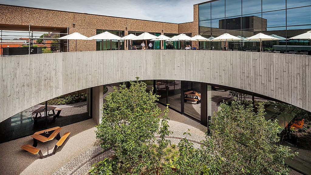 Binnenplaats met twee verdiepingen bij brouwerij Vanhonsebrouck met ankertafels, parasols en centrale beplanting