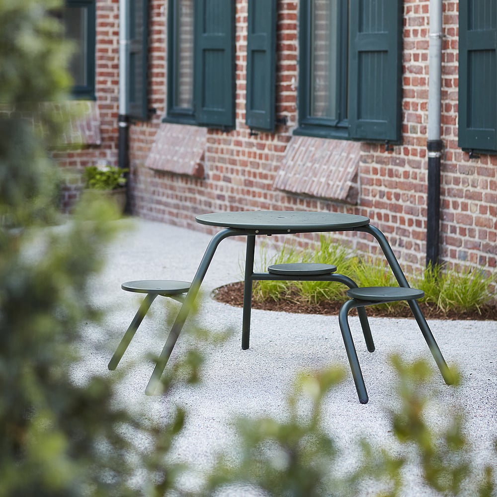 Groene Virus picknicktafel voor 3 personen op een binnenplaats naast een bakstenen gebouw