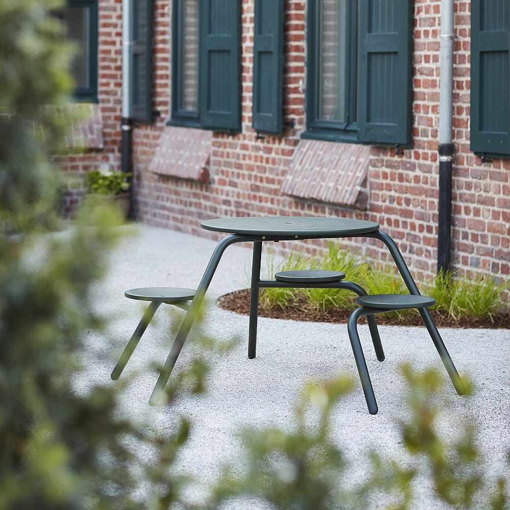 Groene Virus picknicktafel voor 3 personen op een binnenplaats naast een bakstenen gebouw