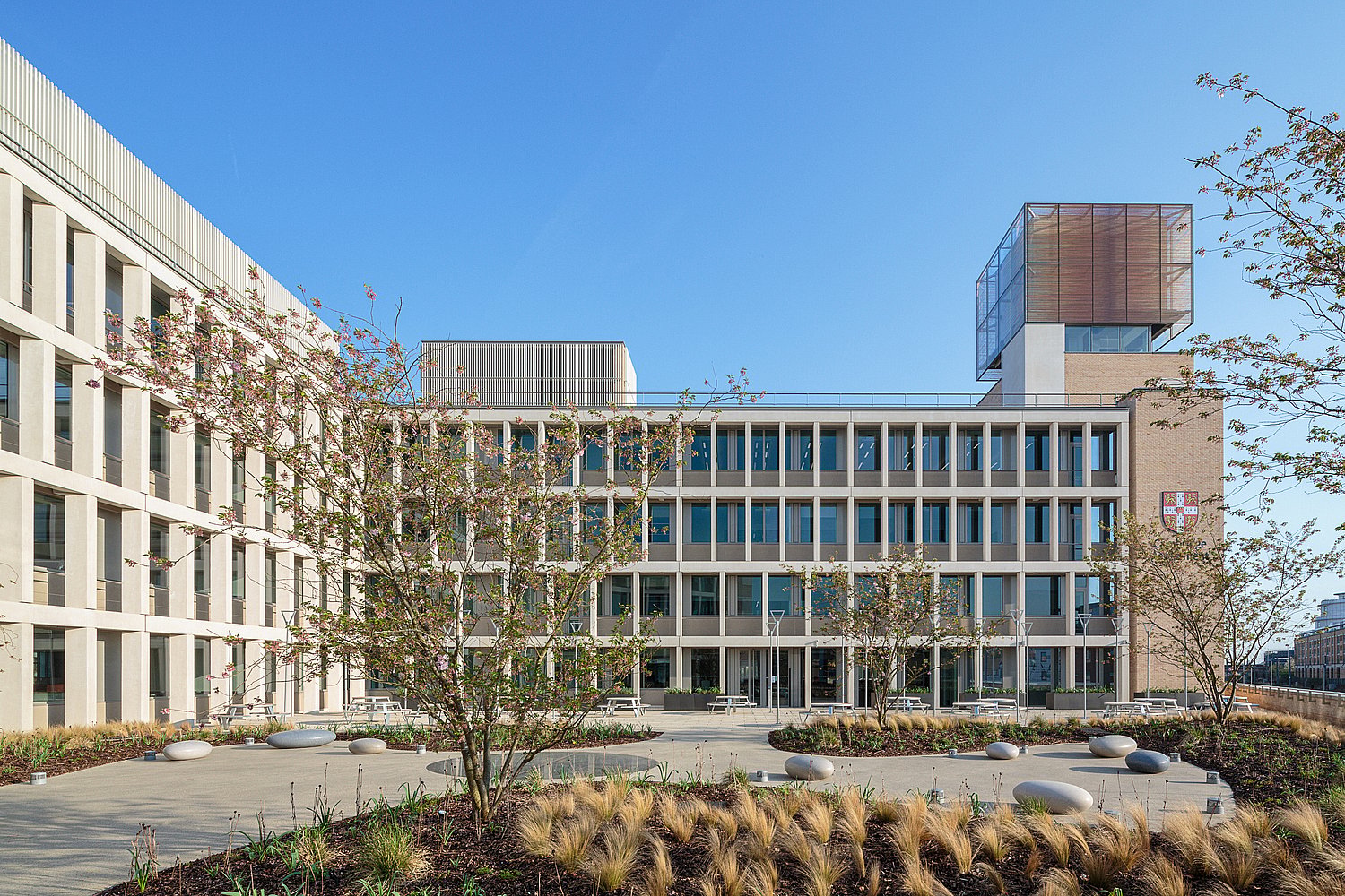 Cambridge Assessment binnenplaats met jonge bomen, siergrassen en Pantagruel picknicktafels bij het gebouw