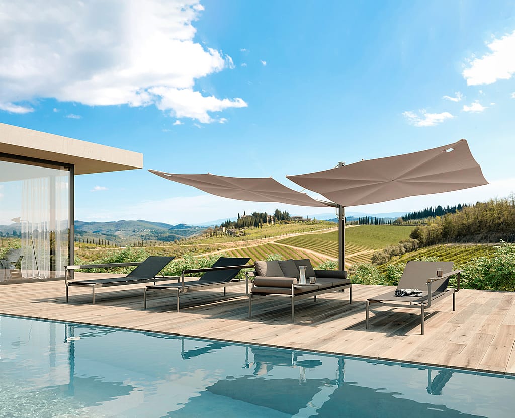Taupe Sensu duo ombrage au-dessus des canapés-transats Sol+Luna sur une terrasse au bord de la piscine avec vue panoramique sur la campagne