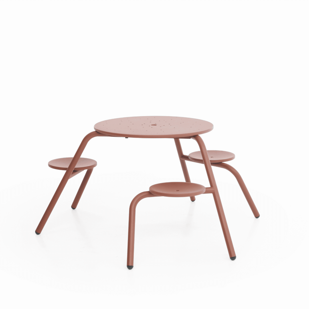 Green Virus 3-seater picnic table in a courtyard beside a brick building