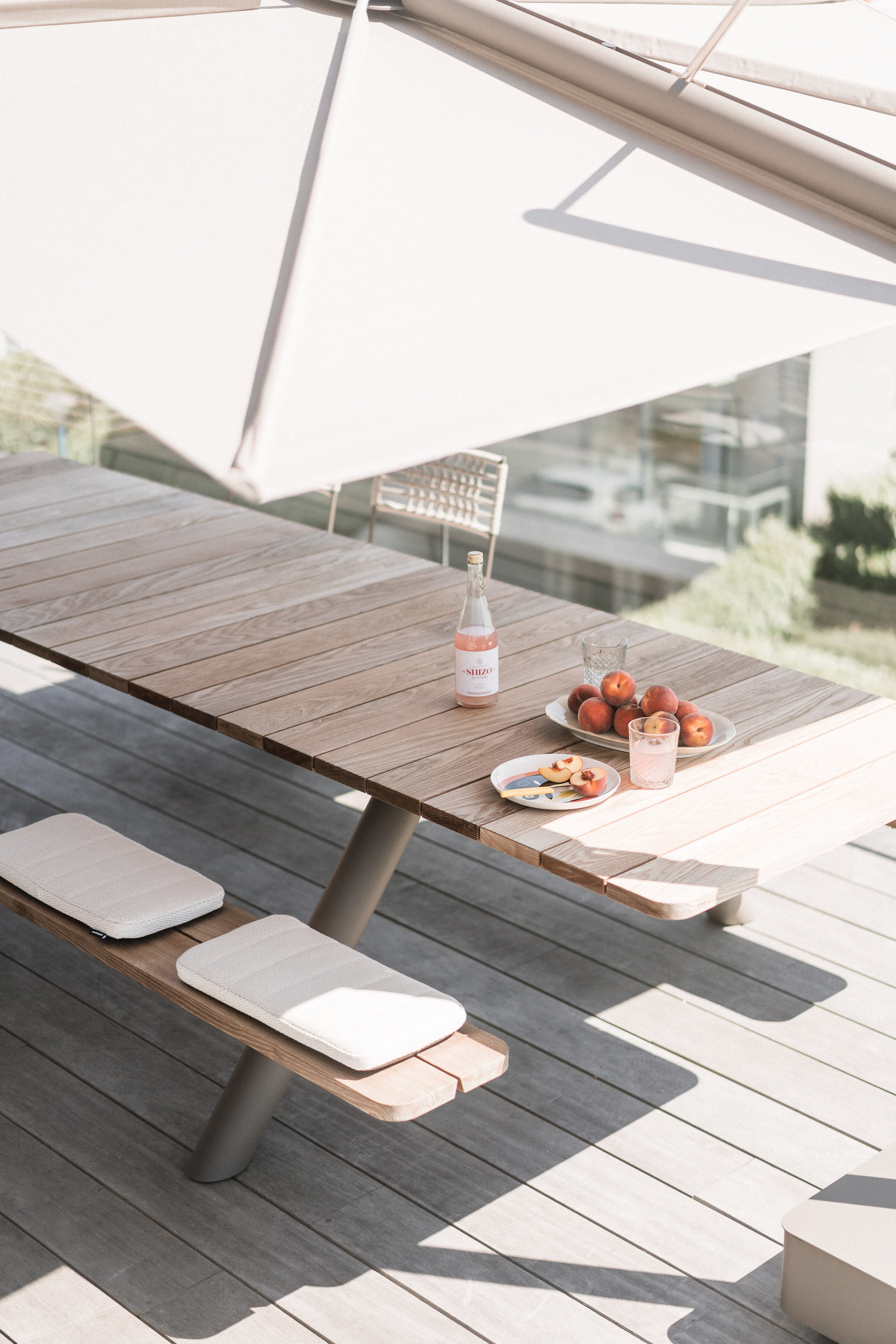 Panigiri picnic table with cushions shaded by a Sensu parasol