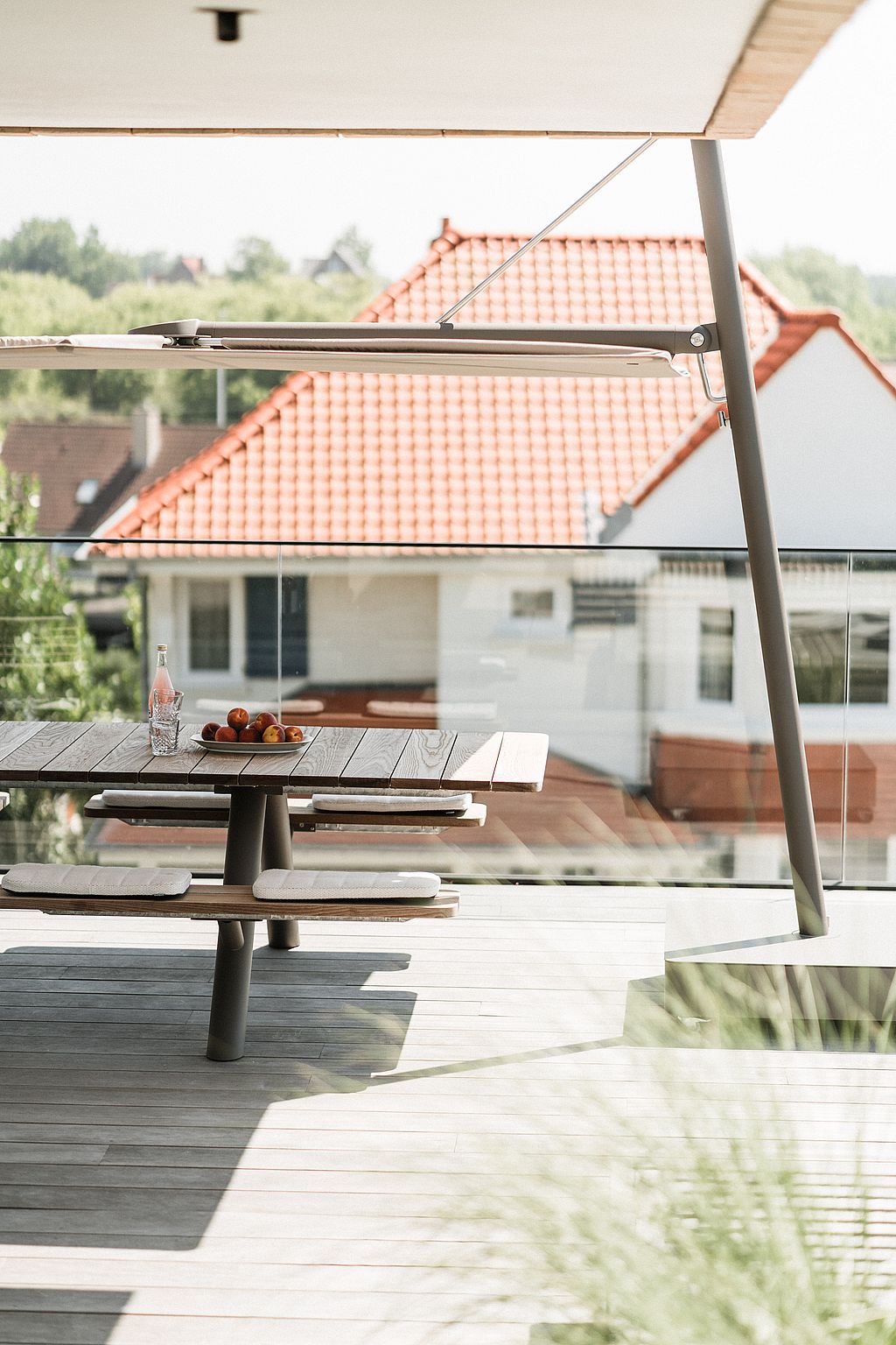 Panigiri picnic table with bench cushions under a Sensu parasol on a rooftop terrace