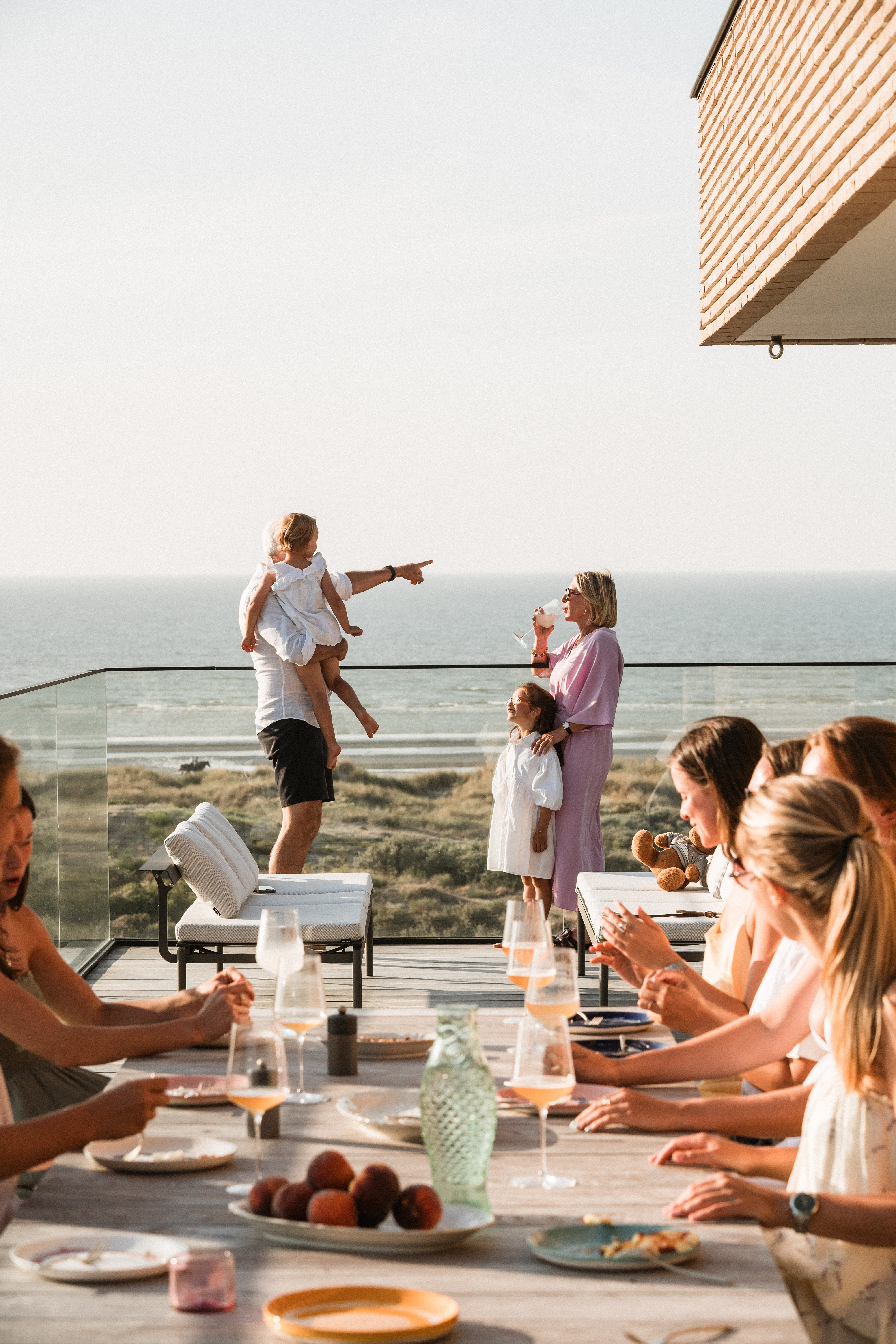 Familie versammelt sich um einen Panigiri-Tisch auf der Terrasse eines Penthouses an der Küste.