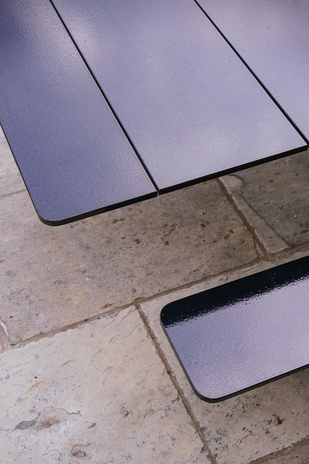 Close-up of the dark glazed lava stone tabletop and bench of Panigiri