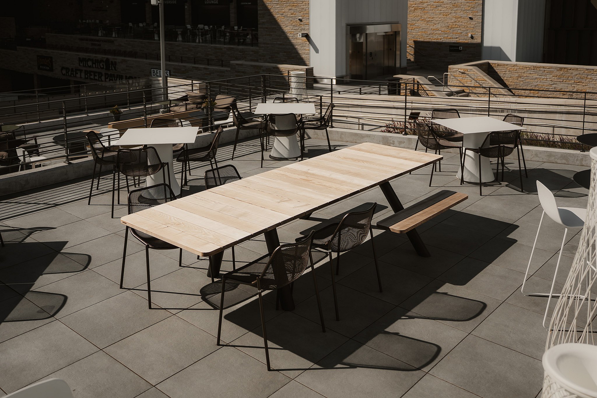 A row of Extremis Panigiri outdoor dining tables with benches and chairs on the terrace at Acrisure Amphitheater