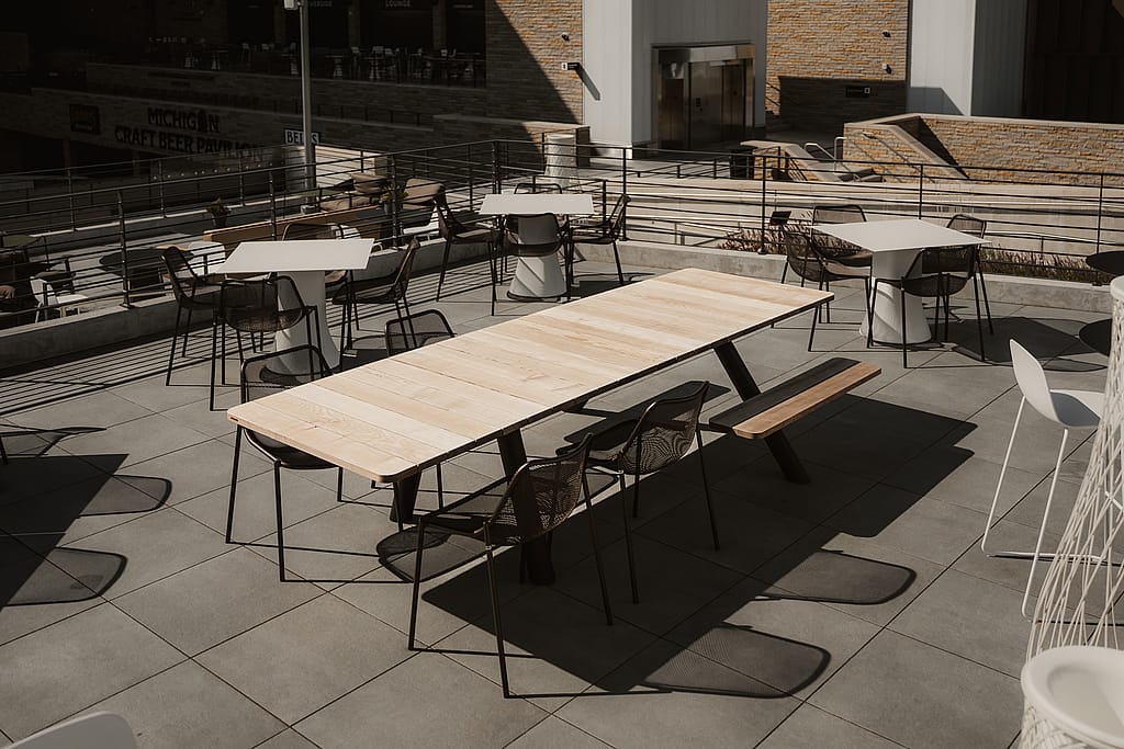 A row of Extremis Panigiri outdoor dining tables with benches and chairs on the terrace at Acrisure Amphitheater
