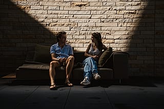 Two guests talking on an Extremis Walrus outdoor sofa against the limestone wall at Acrisure Amphitheater