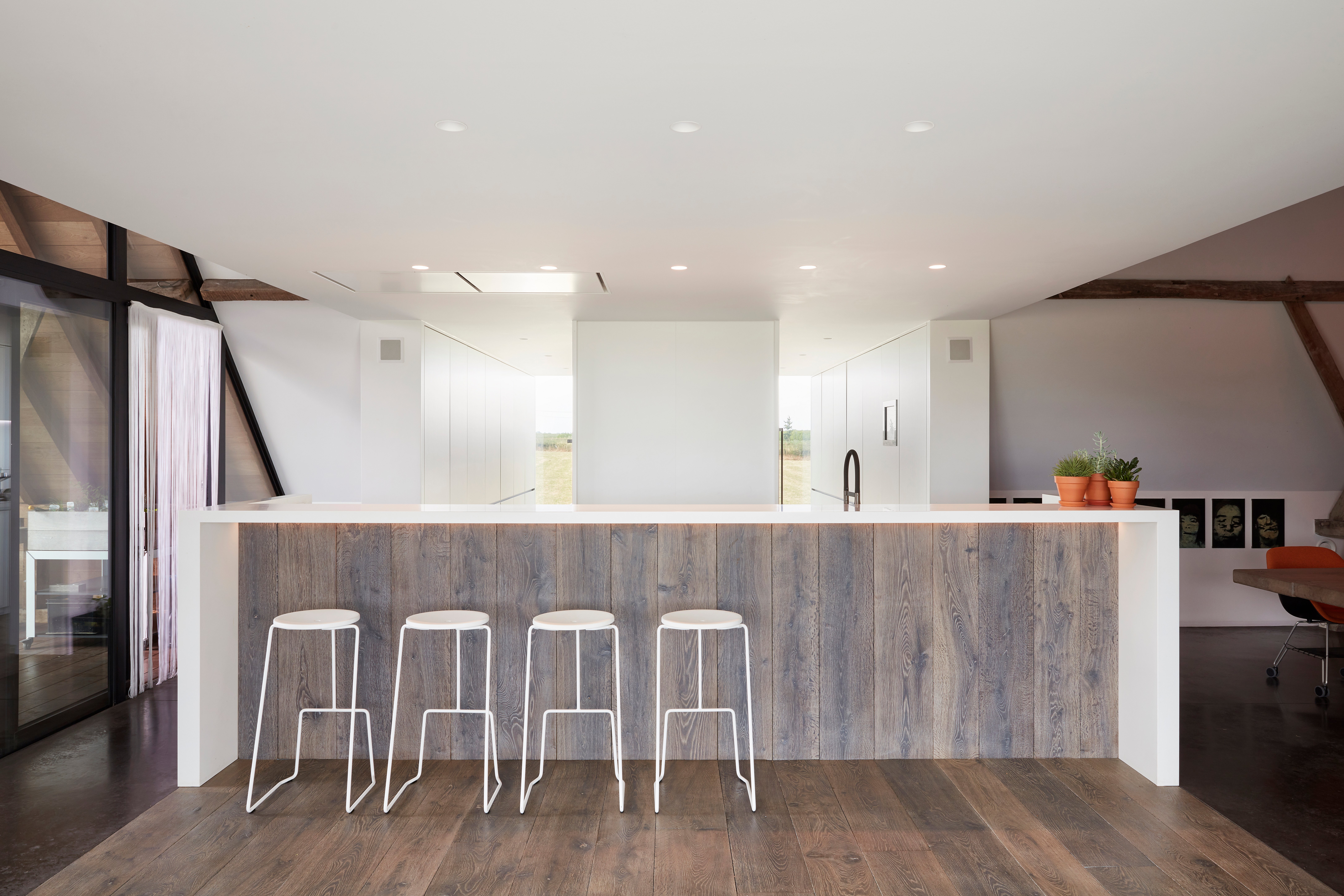 Weiße Tiki Barhocker an einer Küchentheke aus Holz in einem modernen Bauernhausinterieur