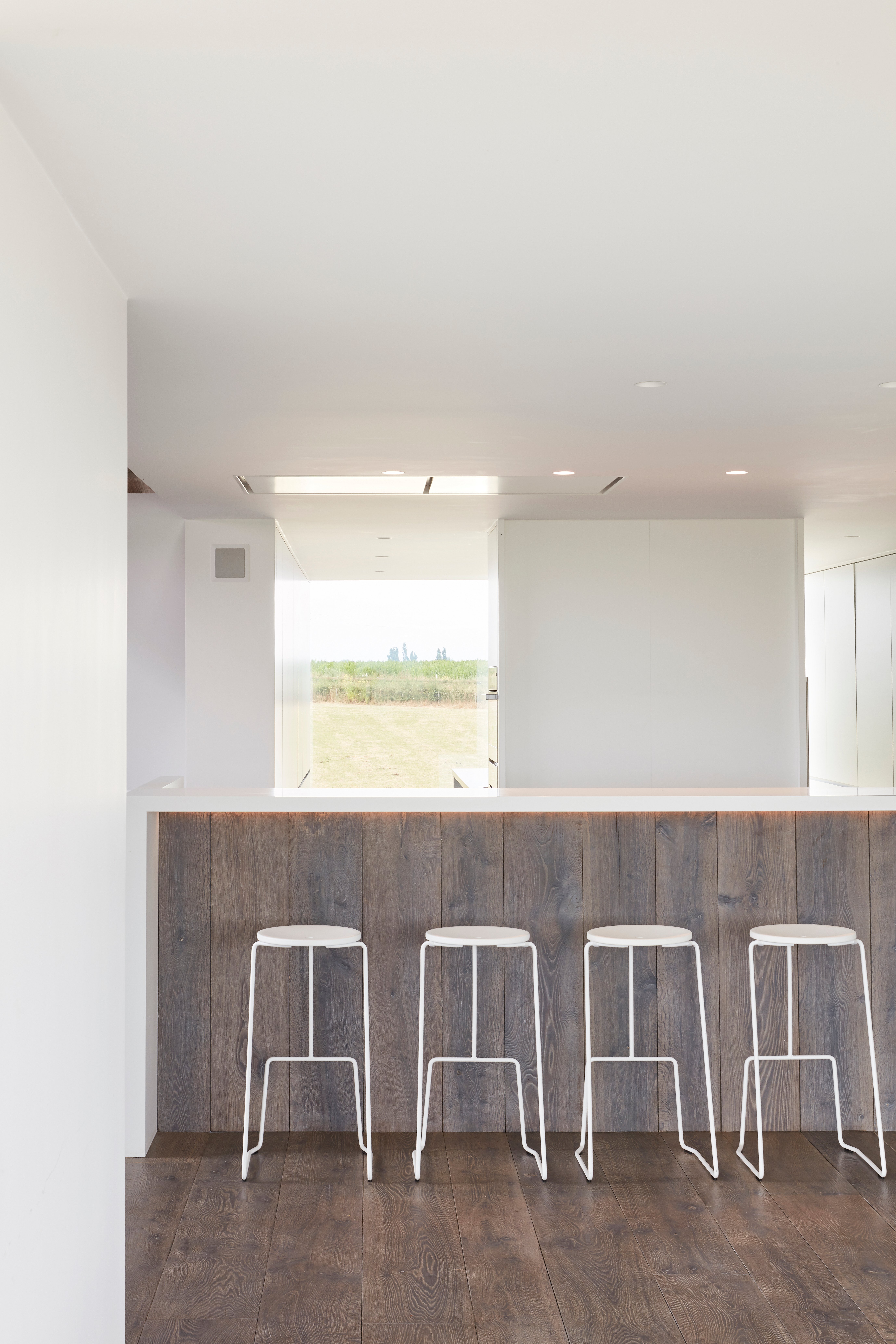 Vier weiße Tiki Barhocker an einer minimalistischen Küchentheke