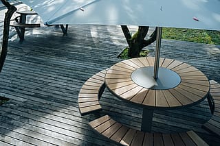 Close-up of a Pantagruel picnic table with wooden benches and central Inumbra parasol