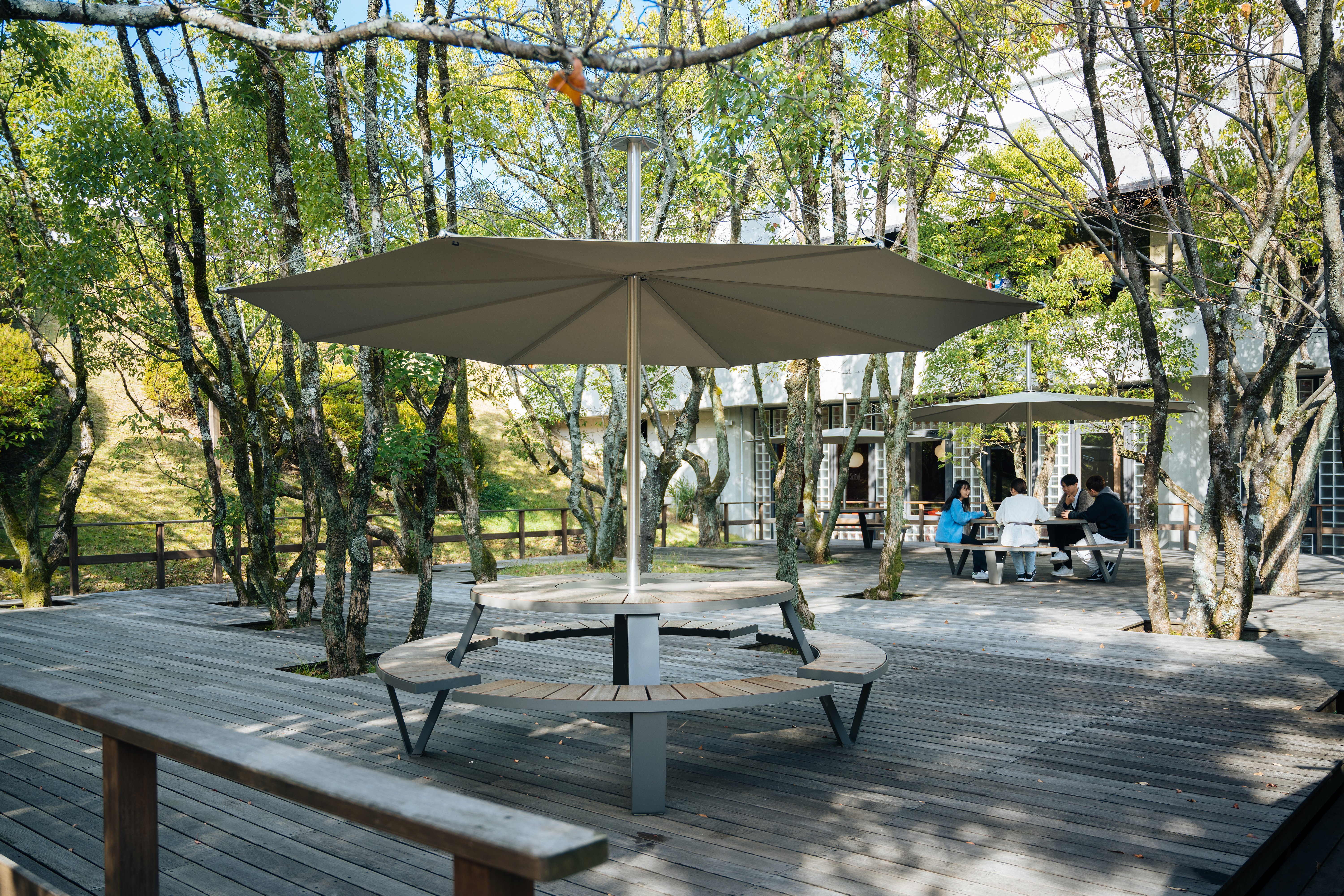 Pantagruel picnic tables with parasols arranged among trees on a wooden deck