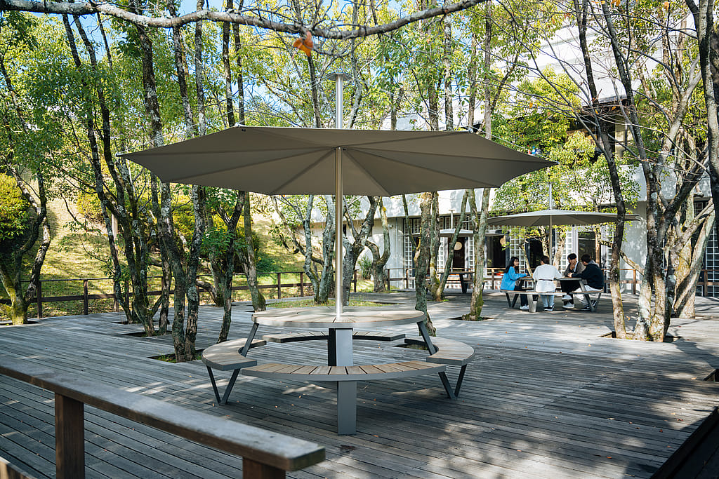 Pantagruel picnic tables with parasols arranged among trees on a wooden deck