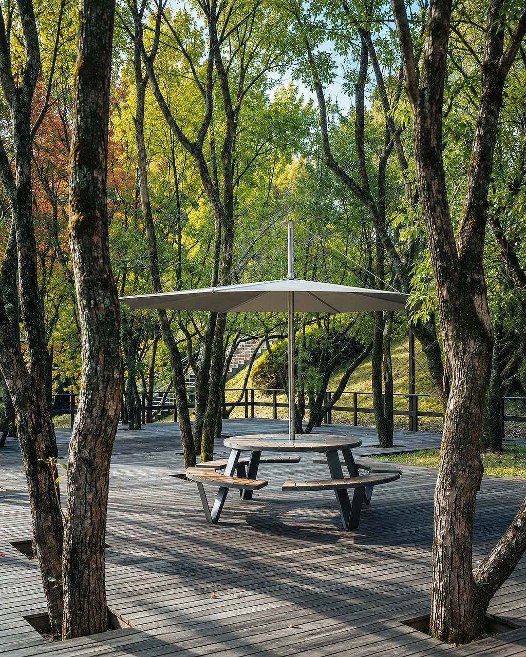 Pantagruel picnic table with integrated benches and central shade on a wooden deck in a wooded setting.