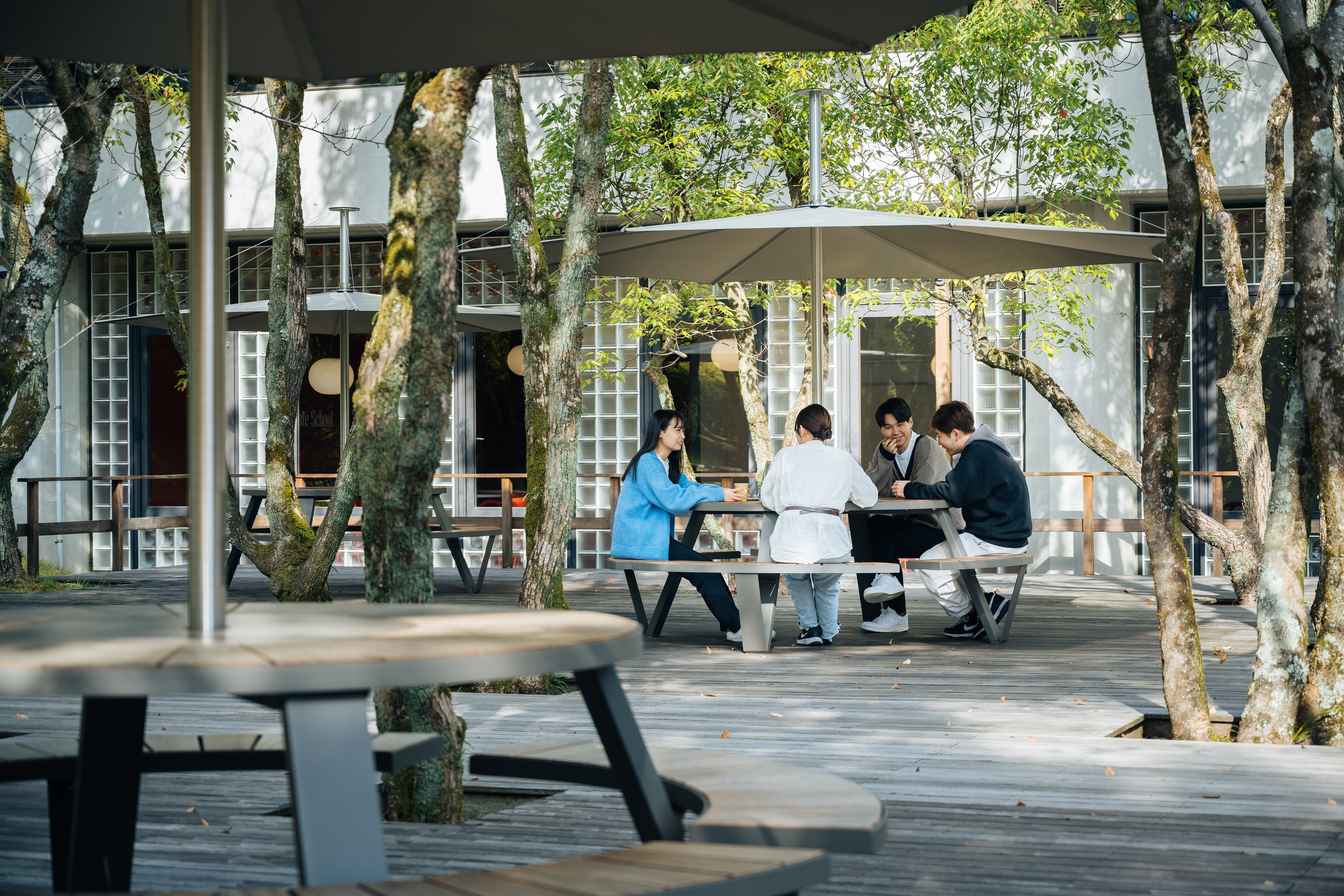 Group of students gathered around a Pantagruel picnic table in a leafy outdoor study area
