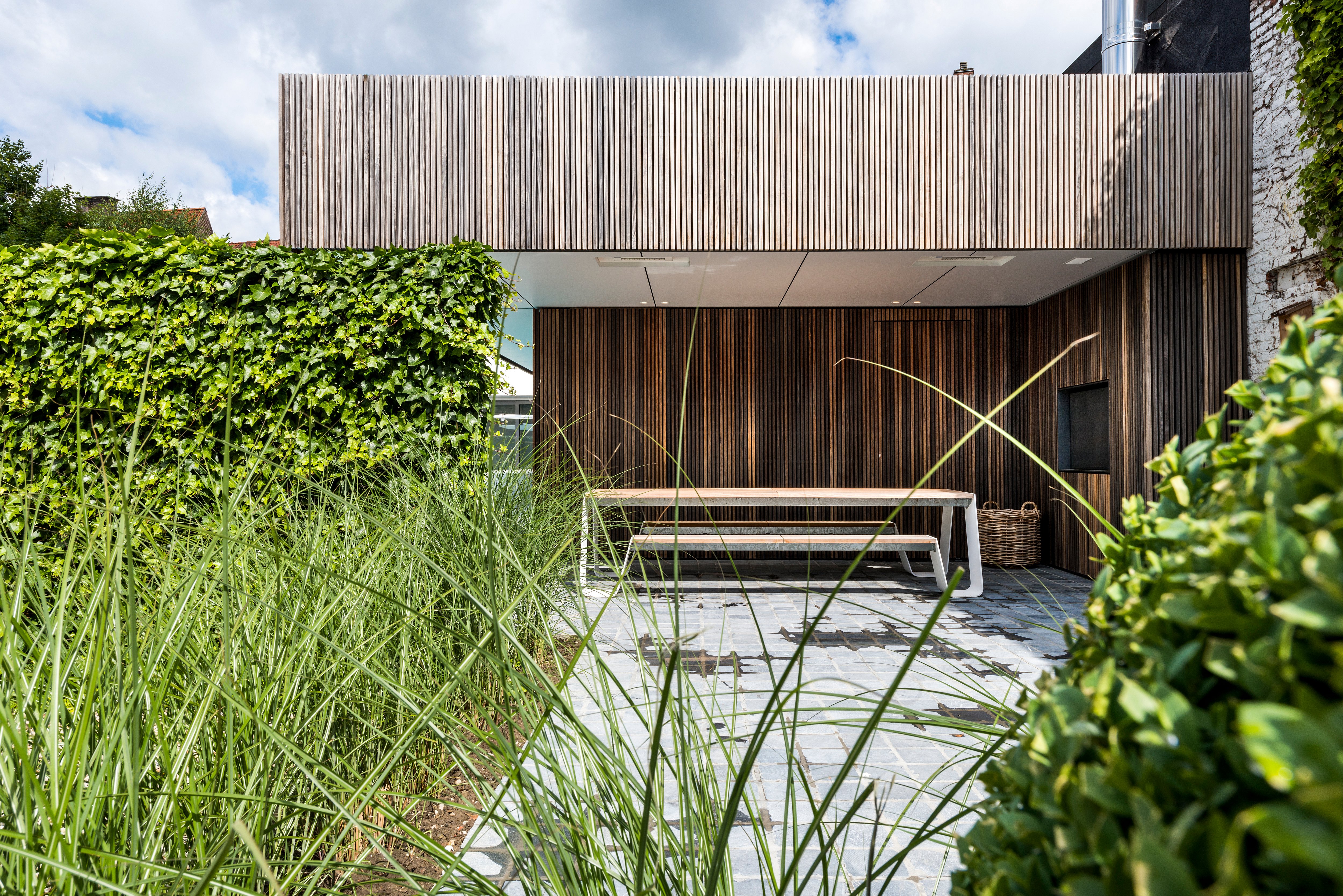 Hopper picnic table under a covered terrace surrounded by lush greenery