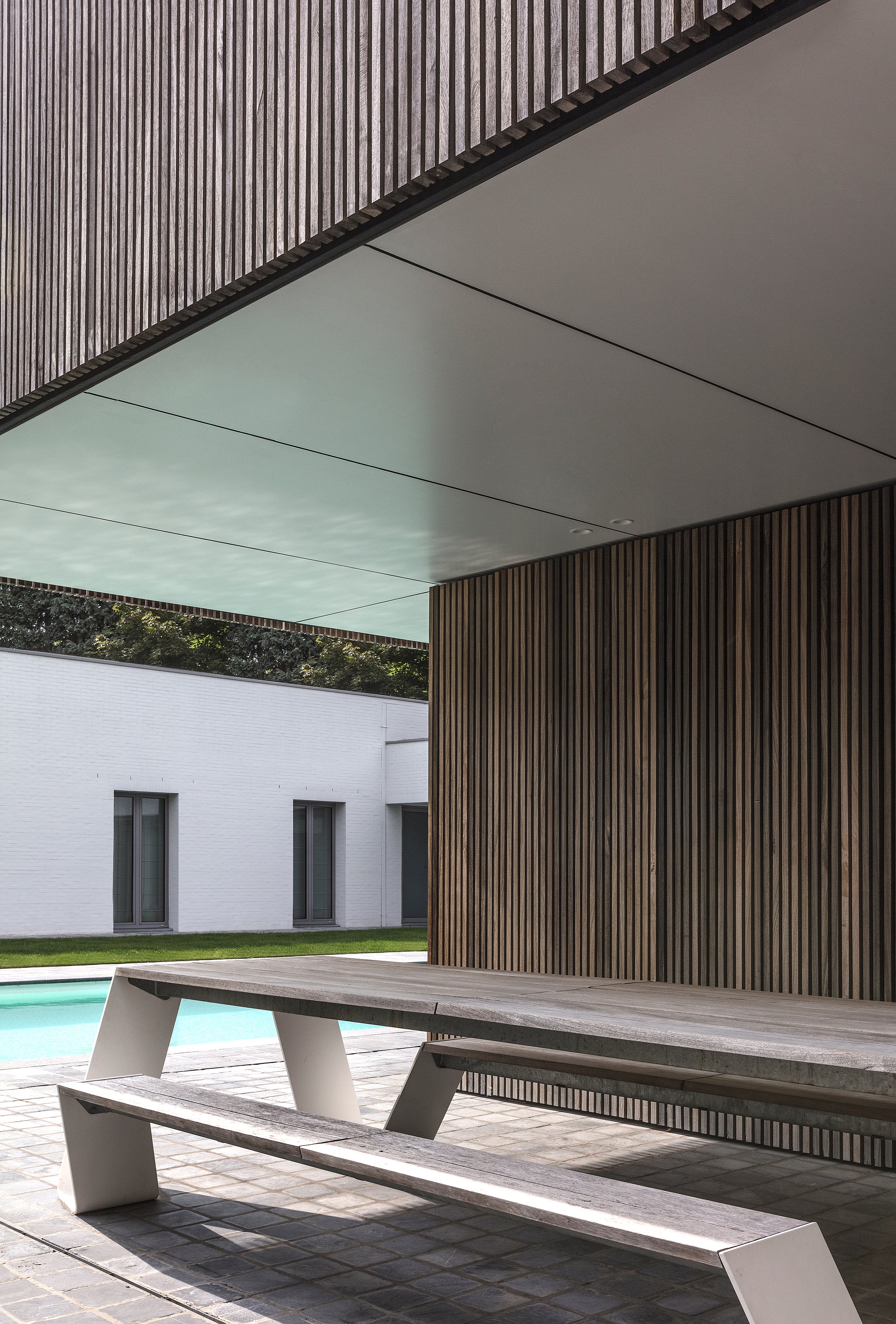 Hopper picnic table in a sheltered pool house overlooking a modern courtyard pool