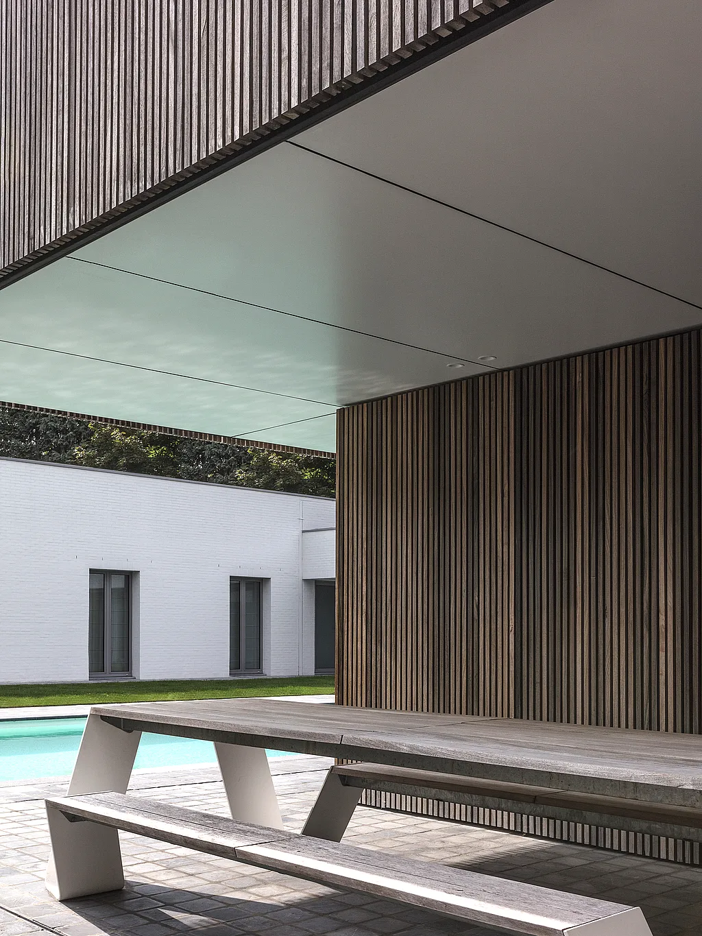 Hopper picnic table in a sheltered pool house overlooking a modern courtyard pool