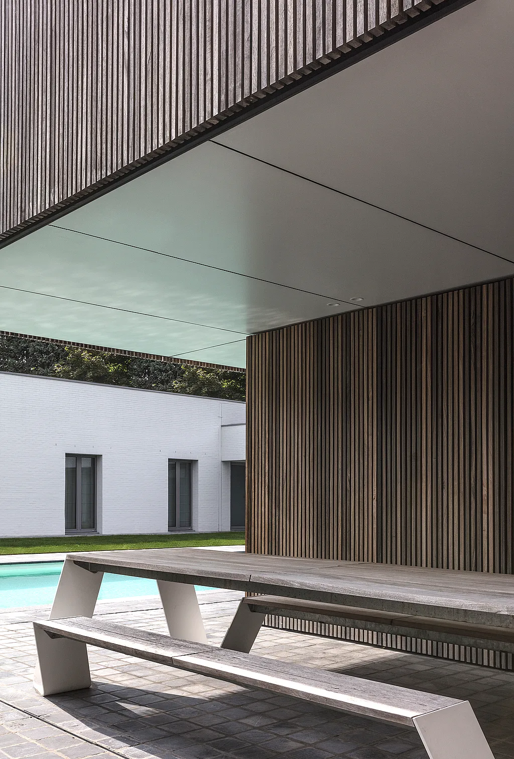 Hopper picnic table in a sheltered pool house overlooking a modern courtyard pool